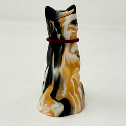 A marbled tortoiseshell Lucky Cat figurine wearing a burgundy collar with a gold letter B charm charm. Rear view.