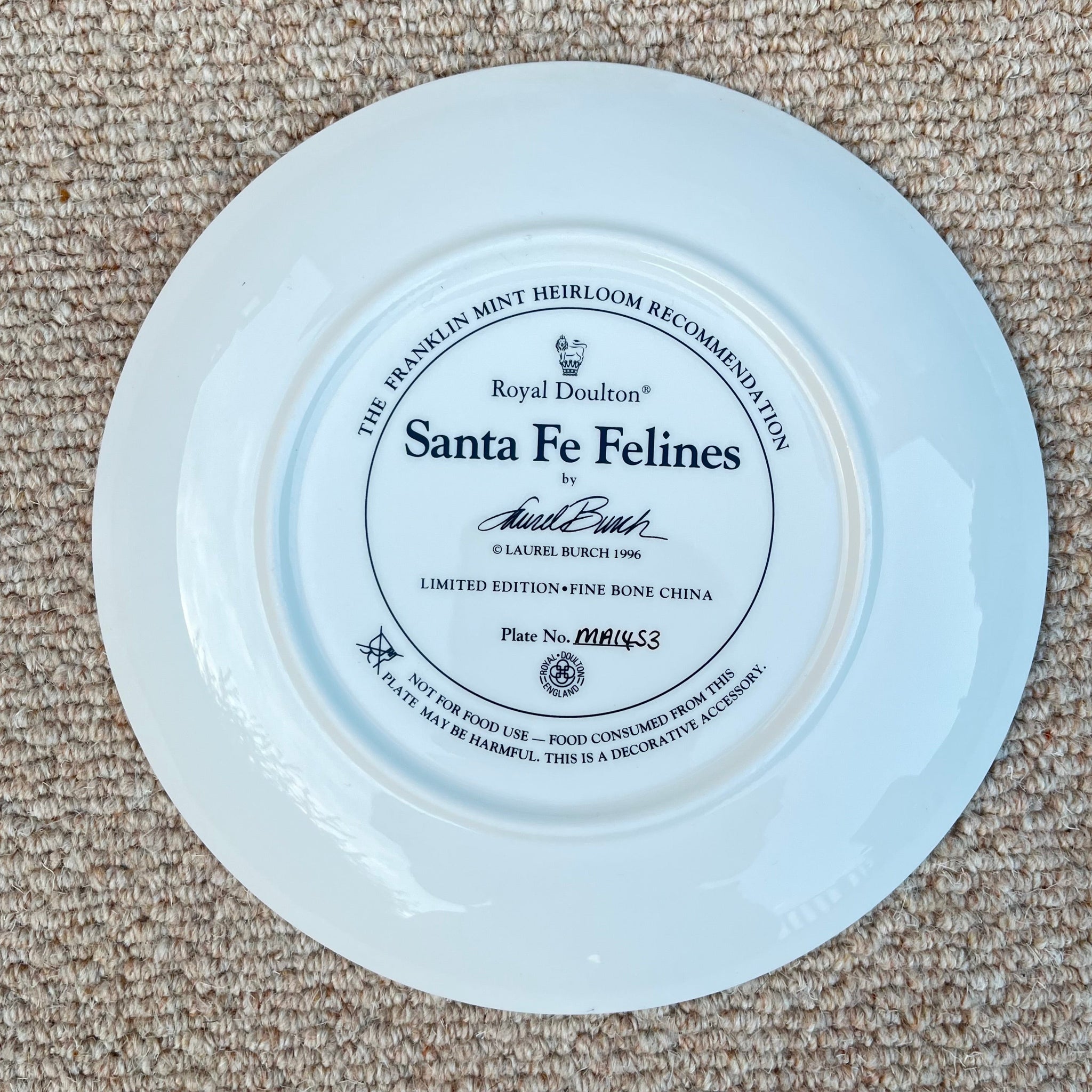 White plate with 'Santa Fe Felines' branding on a beige carpet