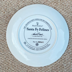 White plate with 'Santa Fe Felines' branding on a beige carpet