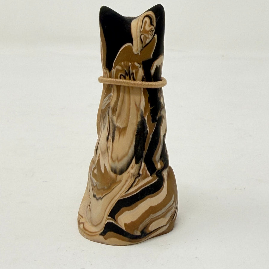 A marbled cream brown and black tabby Lucky Cat figurine wearing a brown collar with a red heart charm. Rear view.