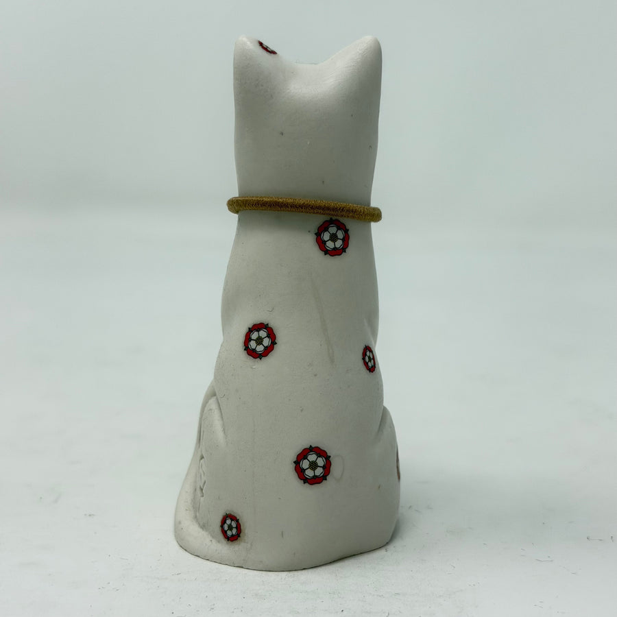 A white resin lucky cat figurine with a brown collar and Yorkshire Rose decoration - rear view