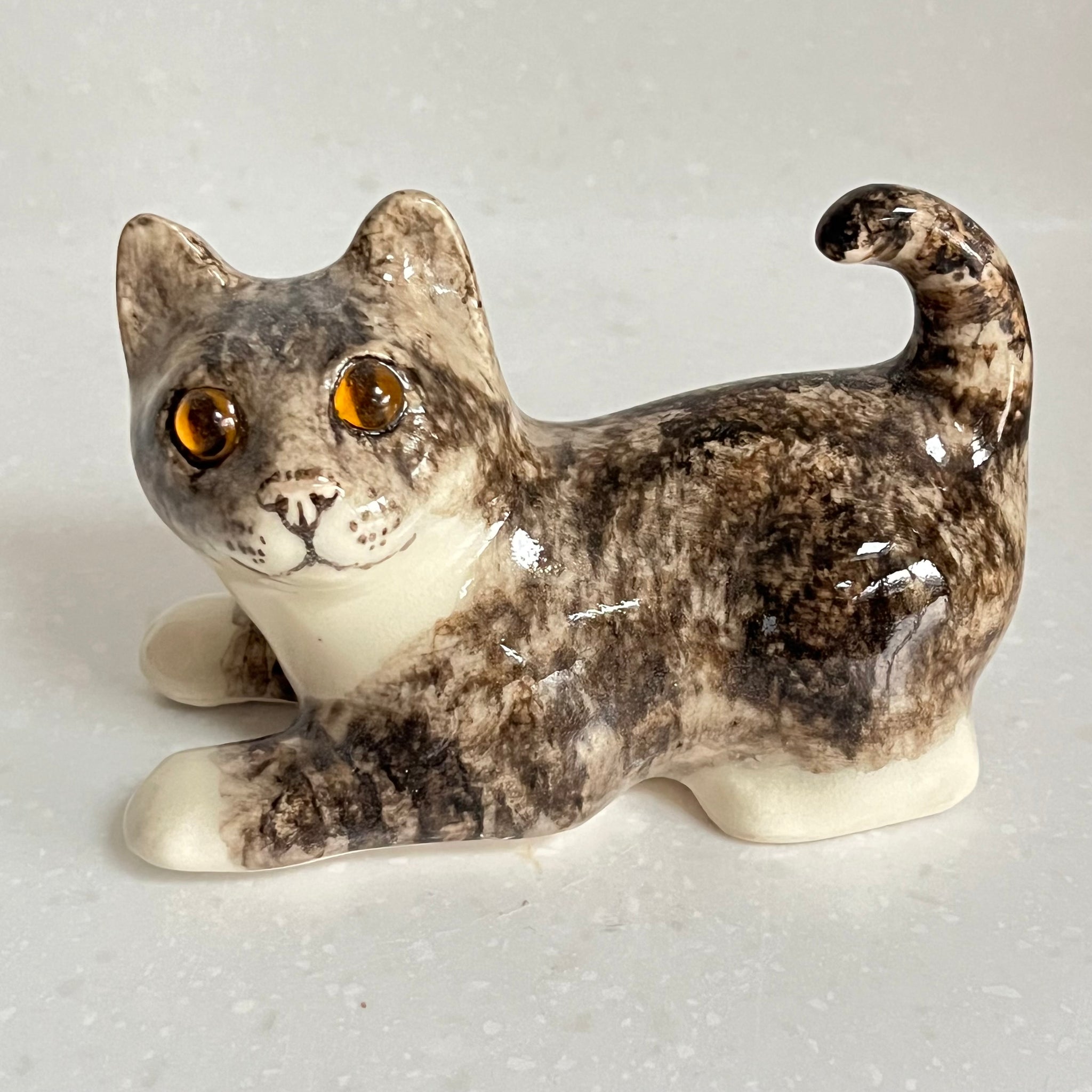 Ceramic cat figurine with a speckled pattern on a light gray background