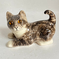 Ceramic cat figurine with a speckled pattern on a light gray background