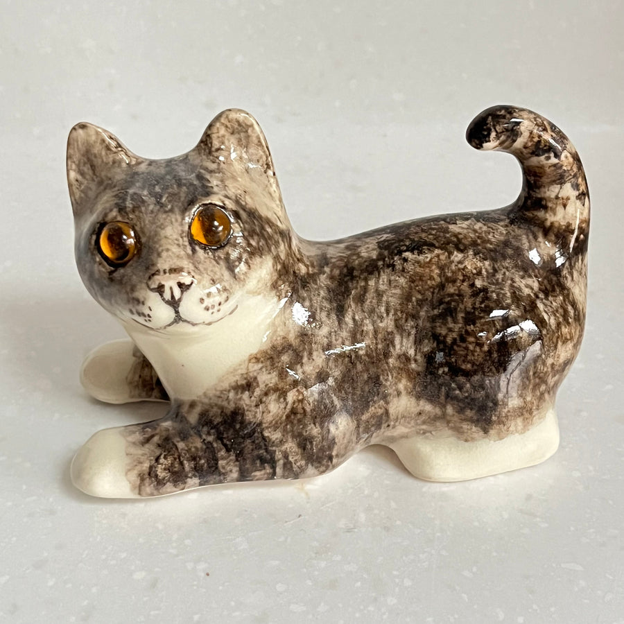 Ceramic cat figurine with a speckled pattern on a light gray background