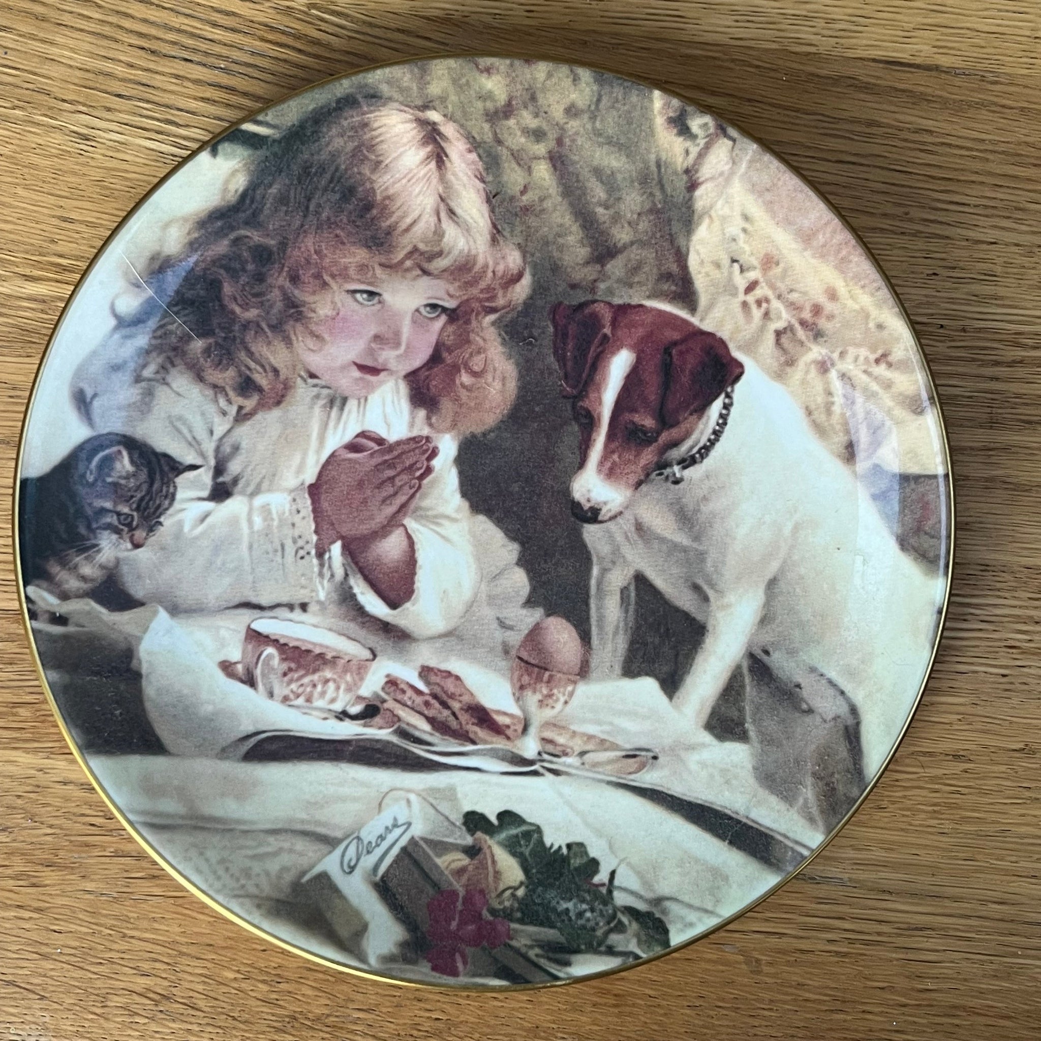 Decorative plate with a vintage-style illustration of a child and dog on a wooden surface