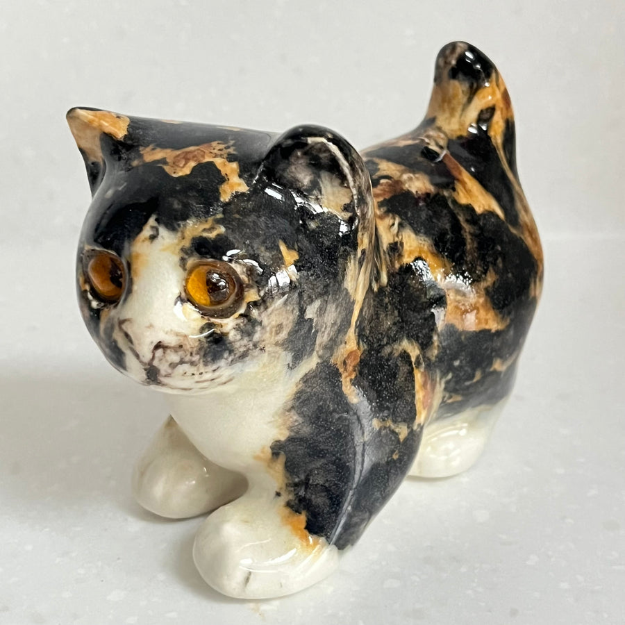 Ceramic cat figurine with tortoiseshell pattern on a white background
