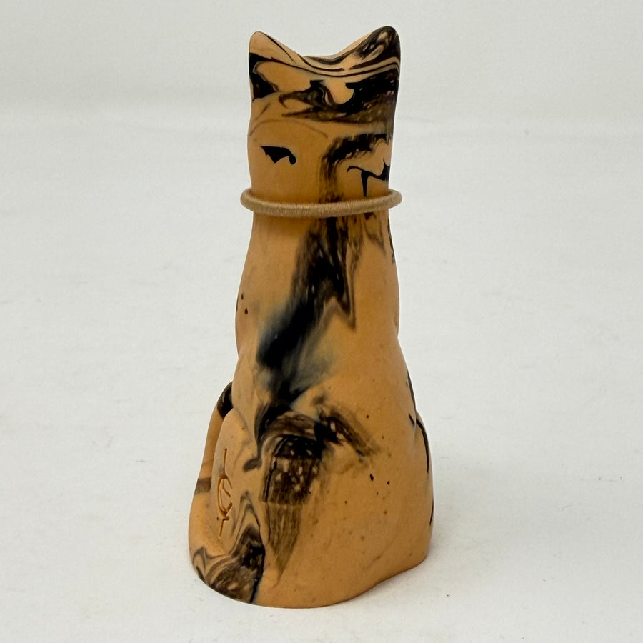 A resin cat figurine with a tan and black marbled pattern, wearing a brown collar with a red heart-shaped charm, set against a plain white background. Rear view.