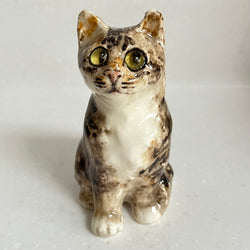 Ceramic cat figurine with green eyes on a white background