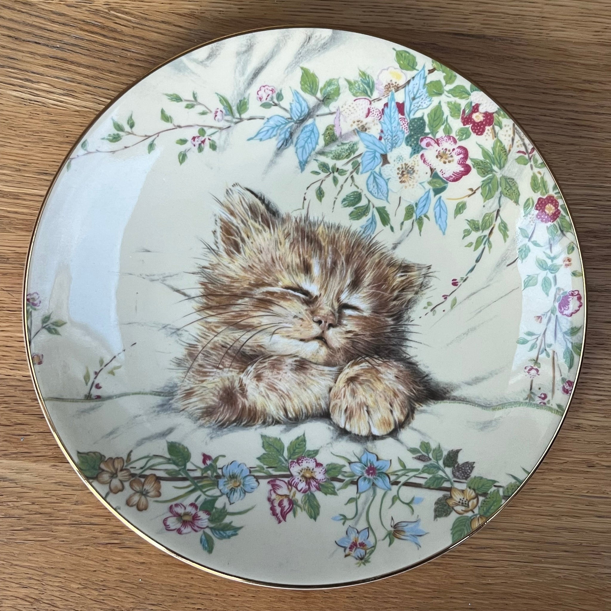 Decorative plate with a cat and floral design on a wooden surface