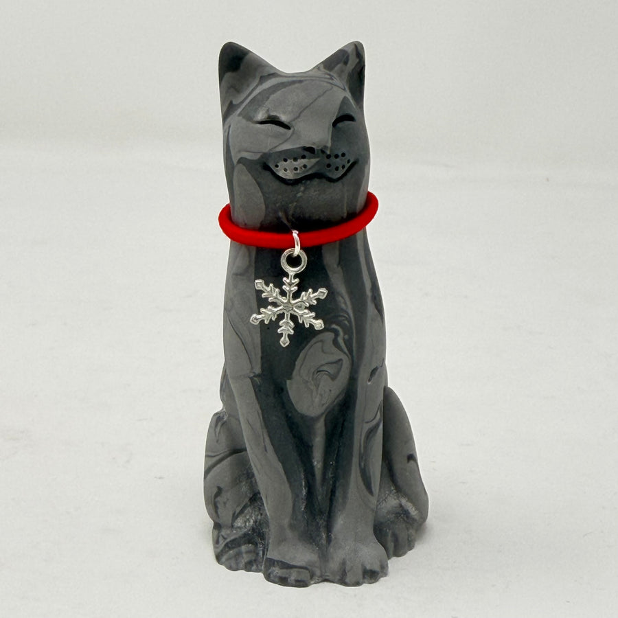 A grey marbled Lucky Cat figurine wearing a red collar with snowflake medallion charm. Front view.