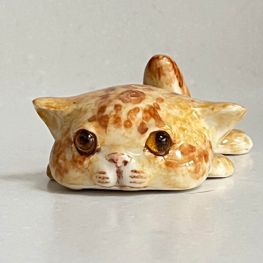 Ceramic cat figurine with brown spots on a light gray background