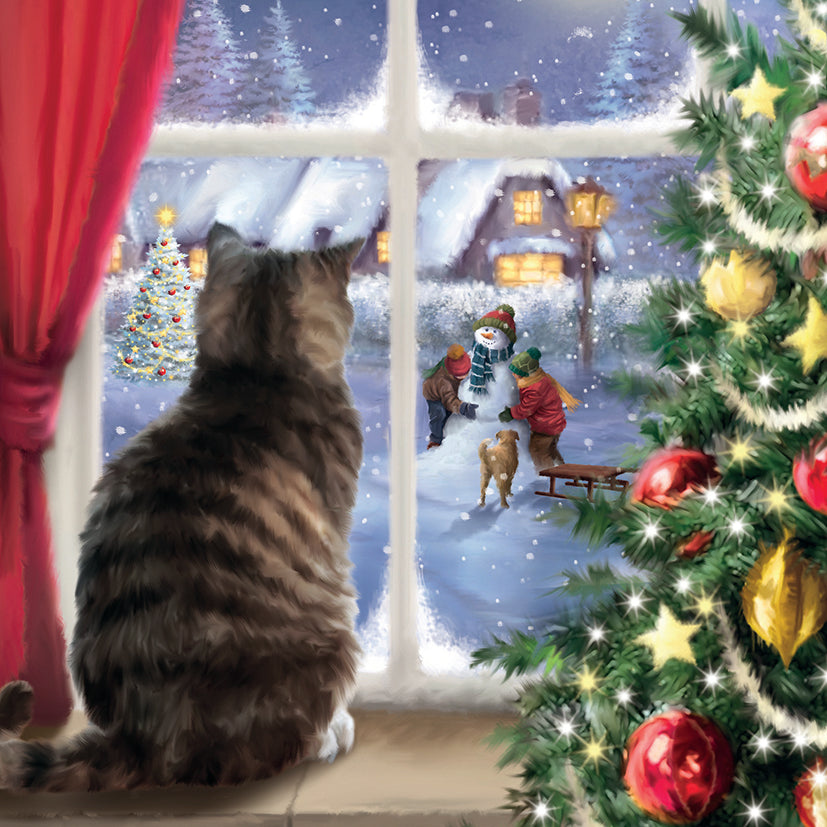 Striped tabby cat looking out a window at a snowy scene with Christmas decorations on a tree.