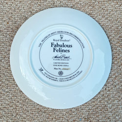 Round ceramic plate with 'Fabulous Felines' branding on a beige carpet