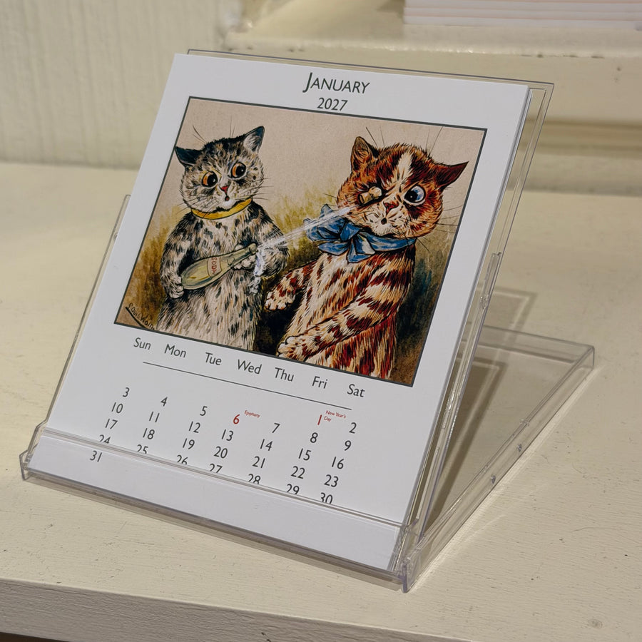 Louis Wain desk calendar folded back for desk display and showing January 2027 - a picture of two tabby cats, one being hit in the eye with a cork from a soda bottle held by the other