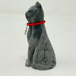 A grey marbled Lucky Cat figurine wearing a red collar with snowflake medallion charm. Side view.