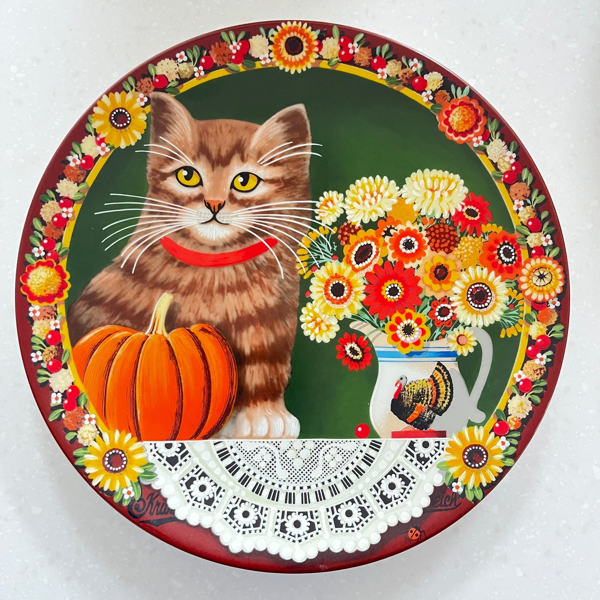 Decorative plate with a cat, pumpkin, and floral design on a white background