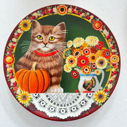 Decorative plate with a cat, pumpkin, and floral design on a white background