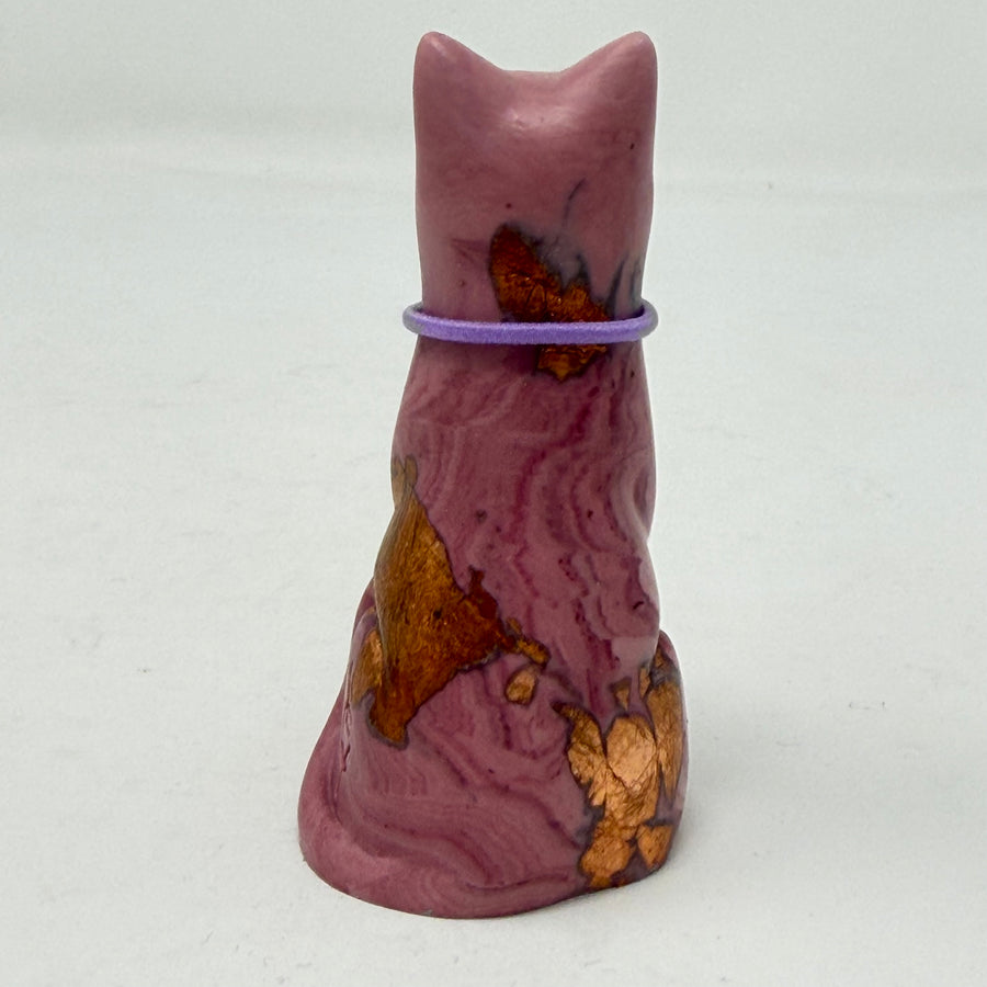 A marbled aubergine-coloured lucky cat figurine wearing a purple collar with a gold letter 'P' charm, set against a plain light grey background. Rear view.