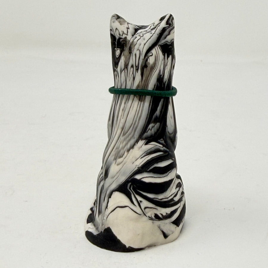 A marbled black and white Lucky Cat figurine wearing a green collar with a green heart charm. Rear view.