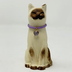 A  Lucky Cat figure hand painted to look like a chocolate point Siamese with a purple collar and heart pendant. Front view.