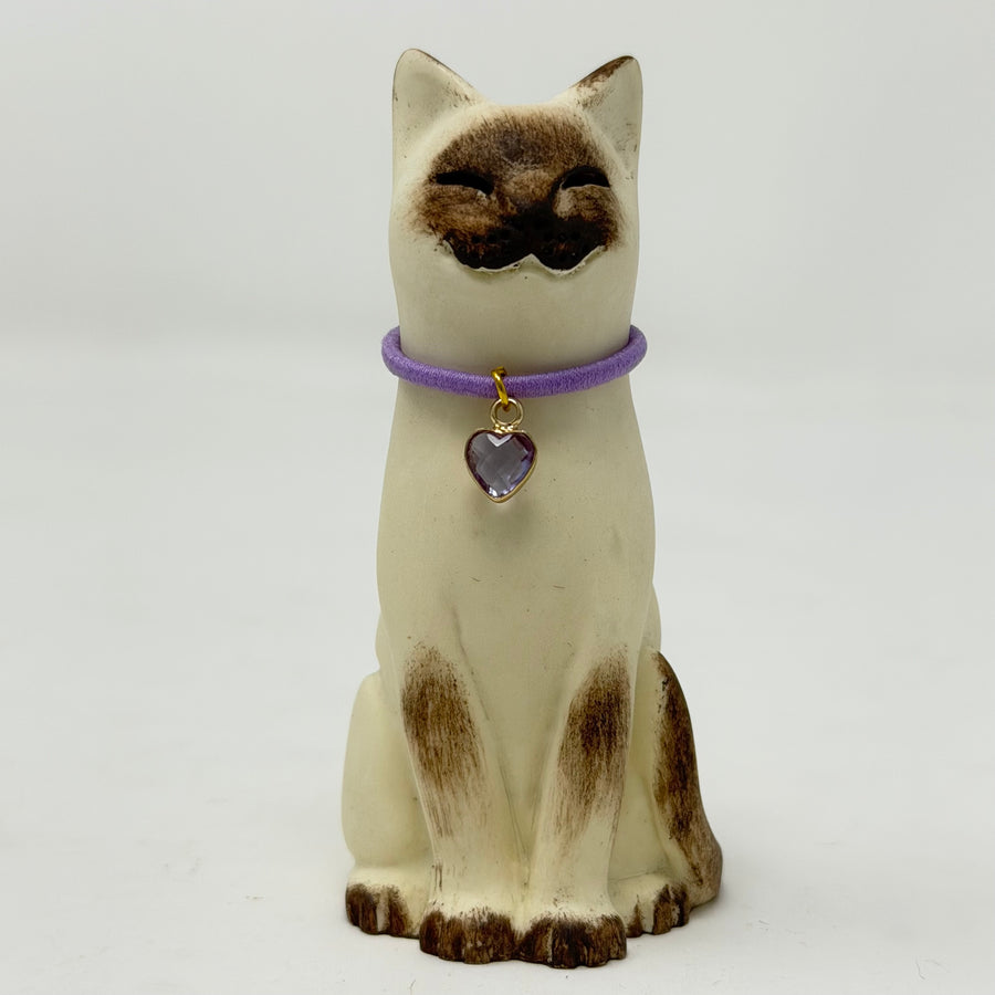 A  Lucky Cat figure hand painted to look like a chocolate point Siamese with a purple collar and heart pendant. Front view.