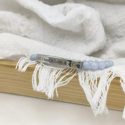 A silver metal bar bracelet engraved with 'All I need is Love & Cat