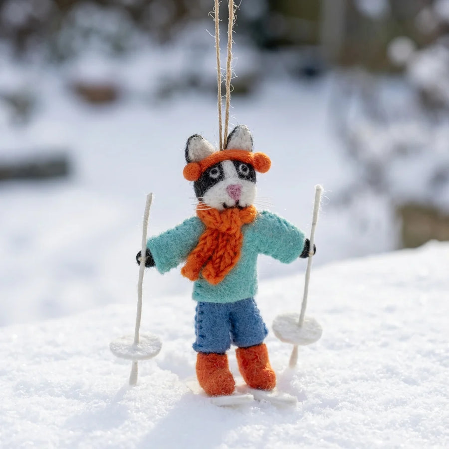 Knitted cat ornament with hanging loop in winter attire on a snowy background