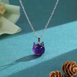 Cat head shaped purple pendant hanging on a silver coloured chain
