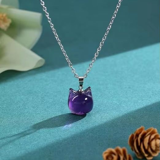Cat head shaped purple pendant hanging on a silver coloured chain