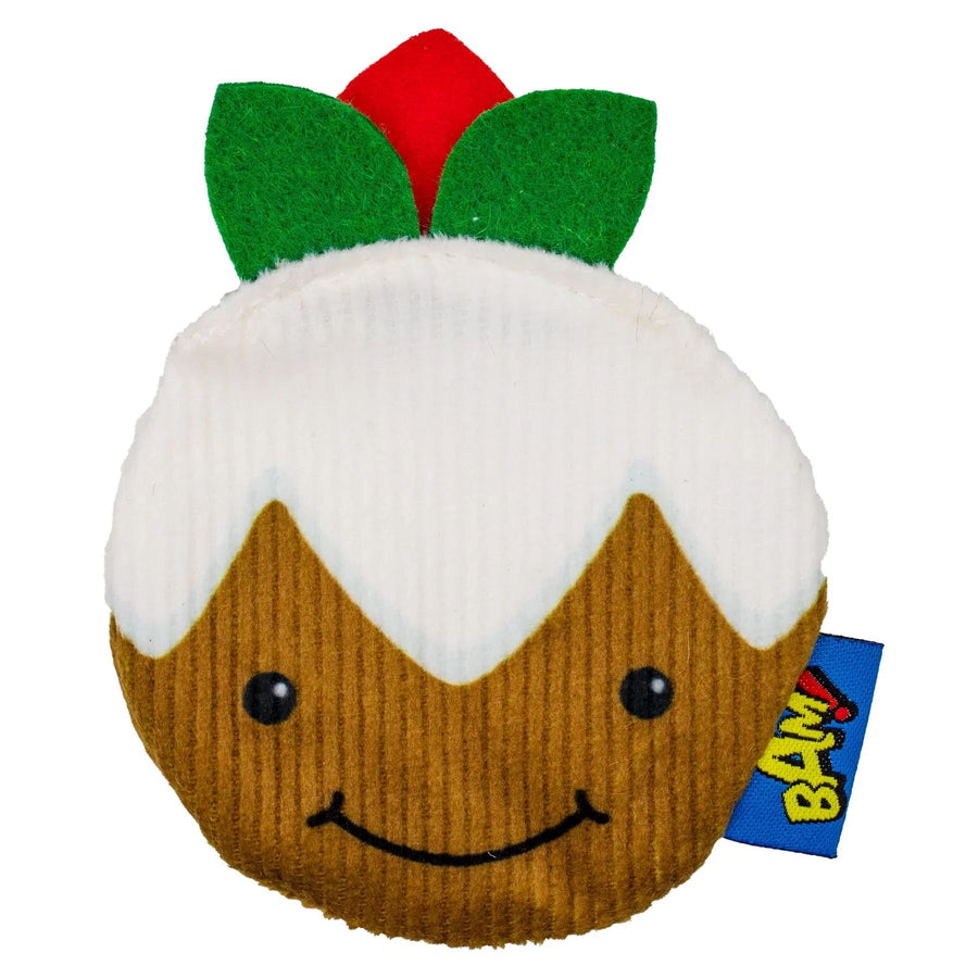 A plush Christmas pudding toy with a brown corduroy body, white faux-frosting, green leaves, and a red ornament on top, with a blue BAM tag attached.