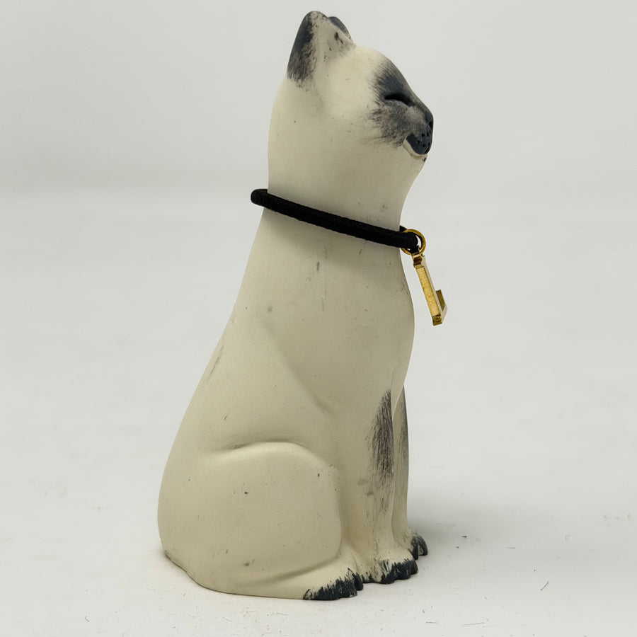 A  Lucky Cat figure hand painted to look like a blue point Siamese with a navy collar and L charm. Side view.