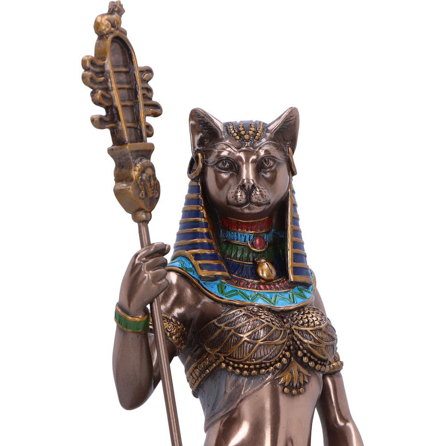 Bronze statue of a cat-like figure with a headdress and staff on a white background