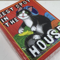 A red deck of cards wrapped in clear plastic, featuring a cartoon cat wearing a blue hat and green pants, with the text 'BEST SPOT IN THE HOUSE' 