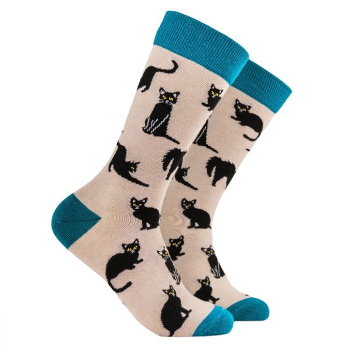 A pair of black cats-themed bamboo socks with a beige background and blue trim.