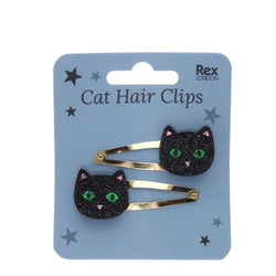 Two black glitter cat hair clips with green eyes and pink nose details, attached to a light blue card labeled 'Cat Hair Clips'