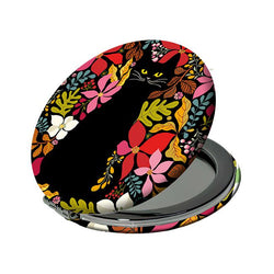 An open round compact mirror with a black lid decorated with a colourful floral and cat pattern