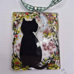 A square glass pendant ornament featuring a black cat silhouette against a white and pink floral background, suspended from gingham ribbon