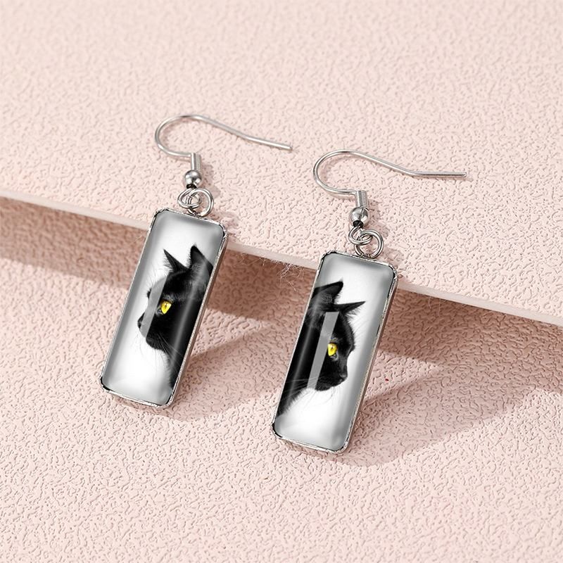 Pair of Black Cat Faces with yellow eyes on a pale pink background