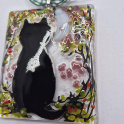 A rectangular glass pendant ornament featuring a black cat silhouette on a white background with pink, green, and yellow floral details