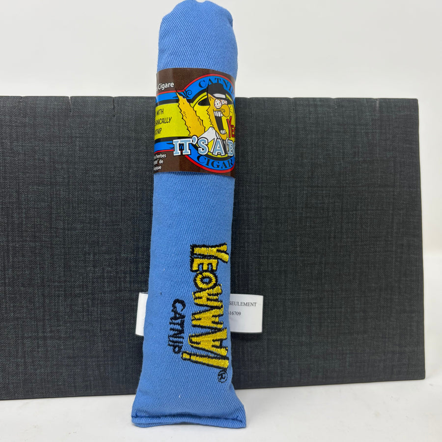 A blue fabric cat toy shaped like a rolled-up tube, standing upright in front of a dark grey block. The toy has a paper band around the middle.
