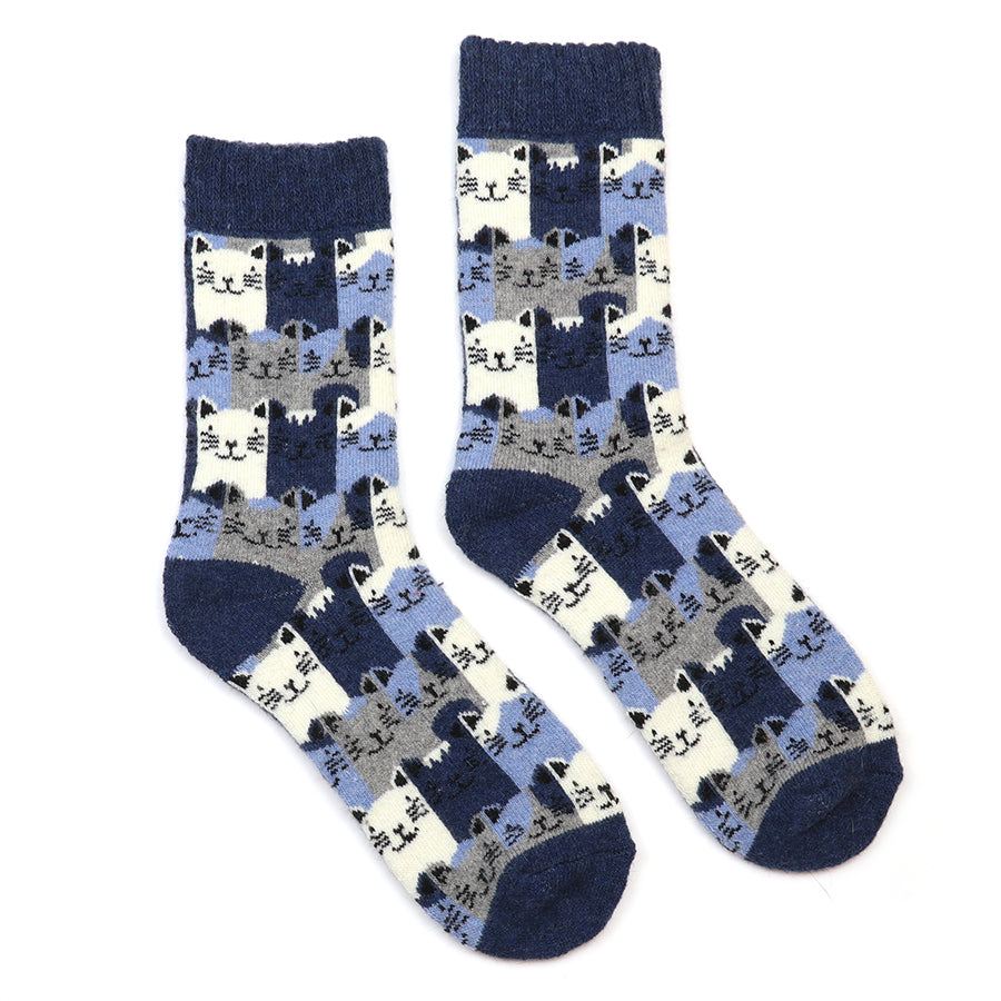 A pair of crew socks with a repeating pattern of cartoon cats in shades of navy, light blue, gray, and cream, set against a plain white background.