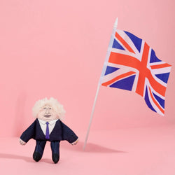 Small Boris Johnson look-a-like figure in a suit with a Union Jack flag against a pink background