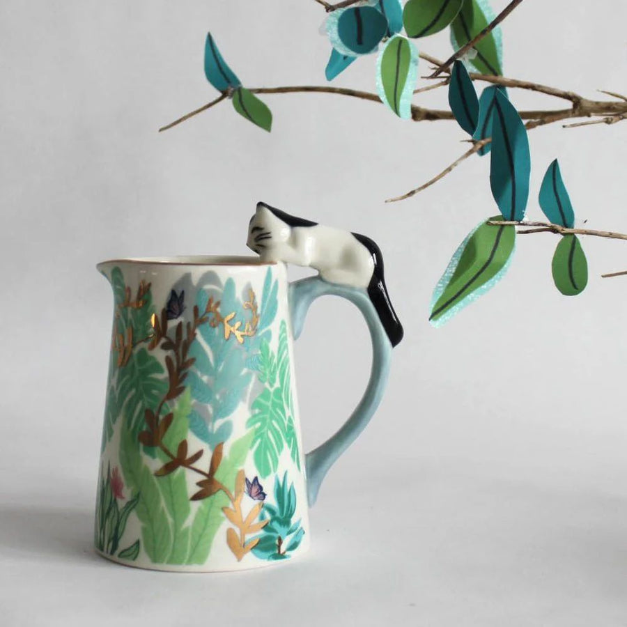 Ceramic pitcher with floral design and cat-shaped spout on a light grey background