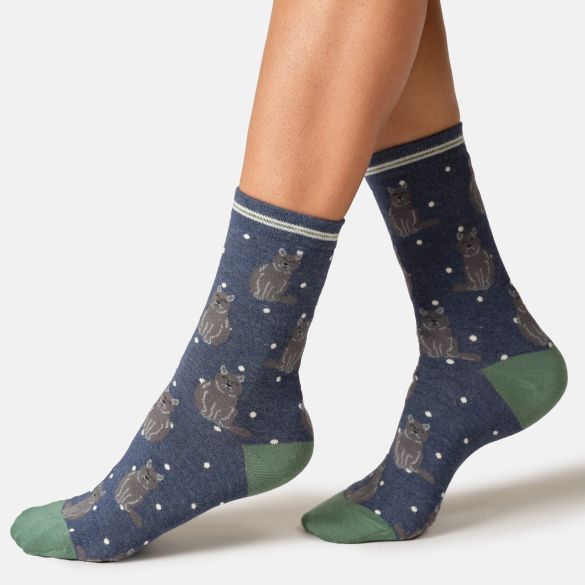 A pair of crew socks worn on a person's feet, featuring a navy blue background with a pattern of grey cats and white dots