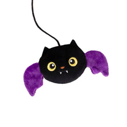 A black plush bat toy with purple wings, yellow eyes, and small white fangs, hanging from a black string against a plain white background.
