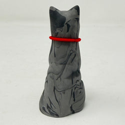 A grey marbled Lucky Cat figurine wearing a red collar with snowflake medallion charm. Rear view.