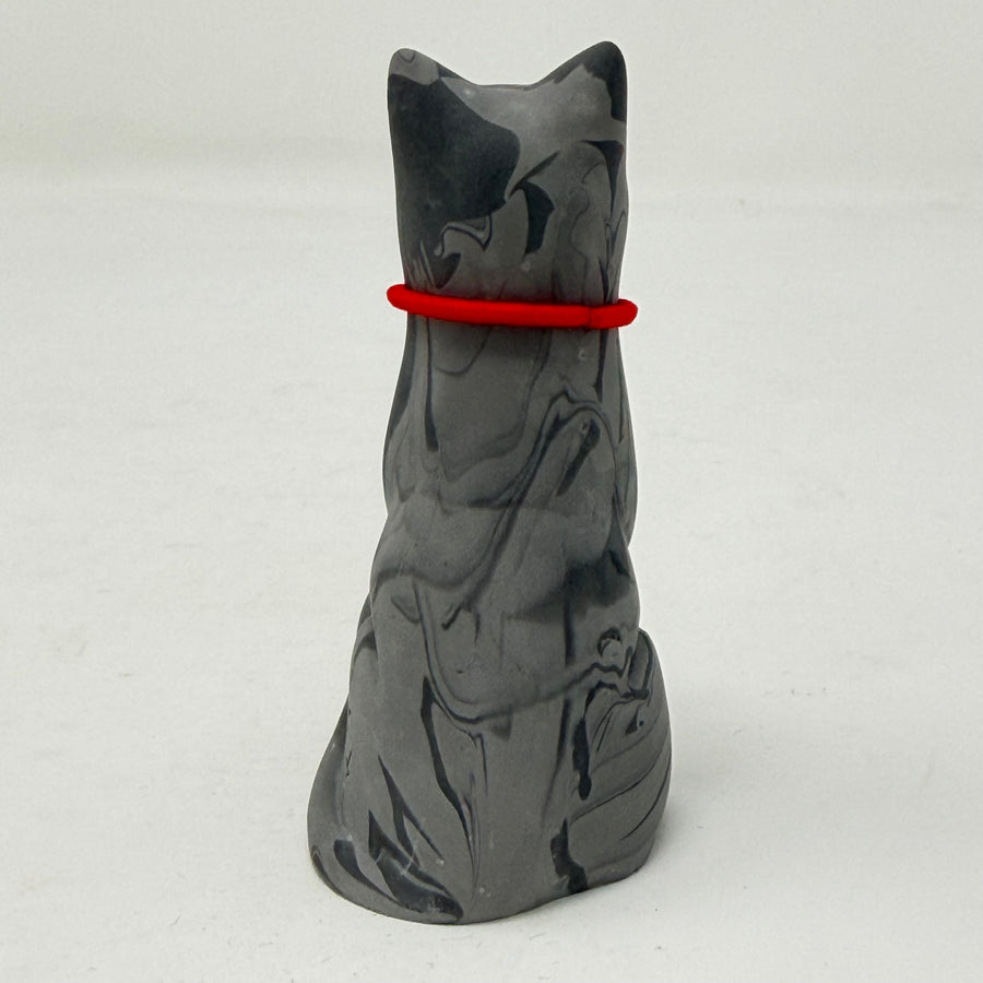 A grey marbled Lucky Cat figurine wearing a red collar with snowflake medallion charm. Rear view.