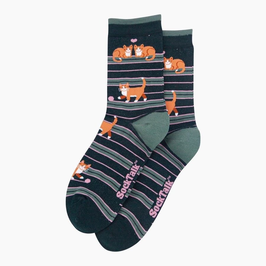A pair of dark navy crew socks with horizontal stripes in gray, olive green, and pink, featuring cartoon orange tabby cats