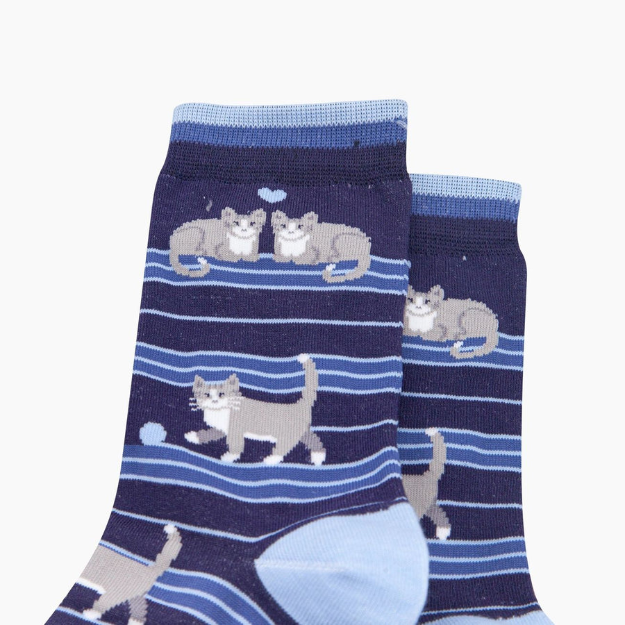 A pair of navy blue crew socks with a pattern of gray and white cats on horizontal blue stripes