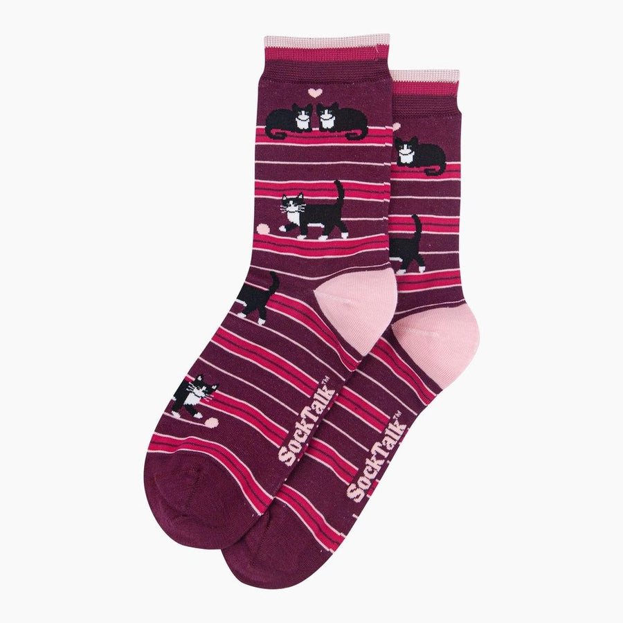 A pair of crew socks with a burgundy and pink striped pattern, featuring cartoon black-and-white cats